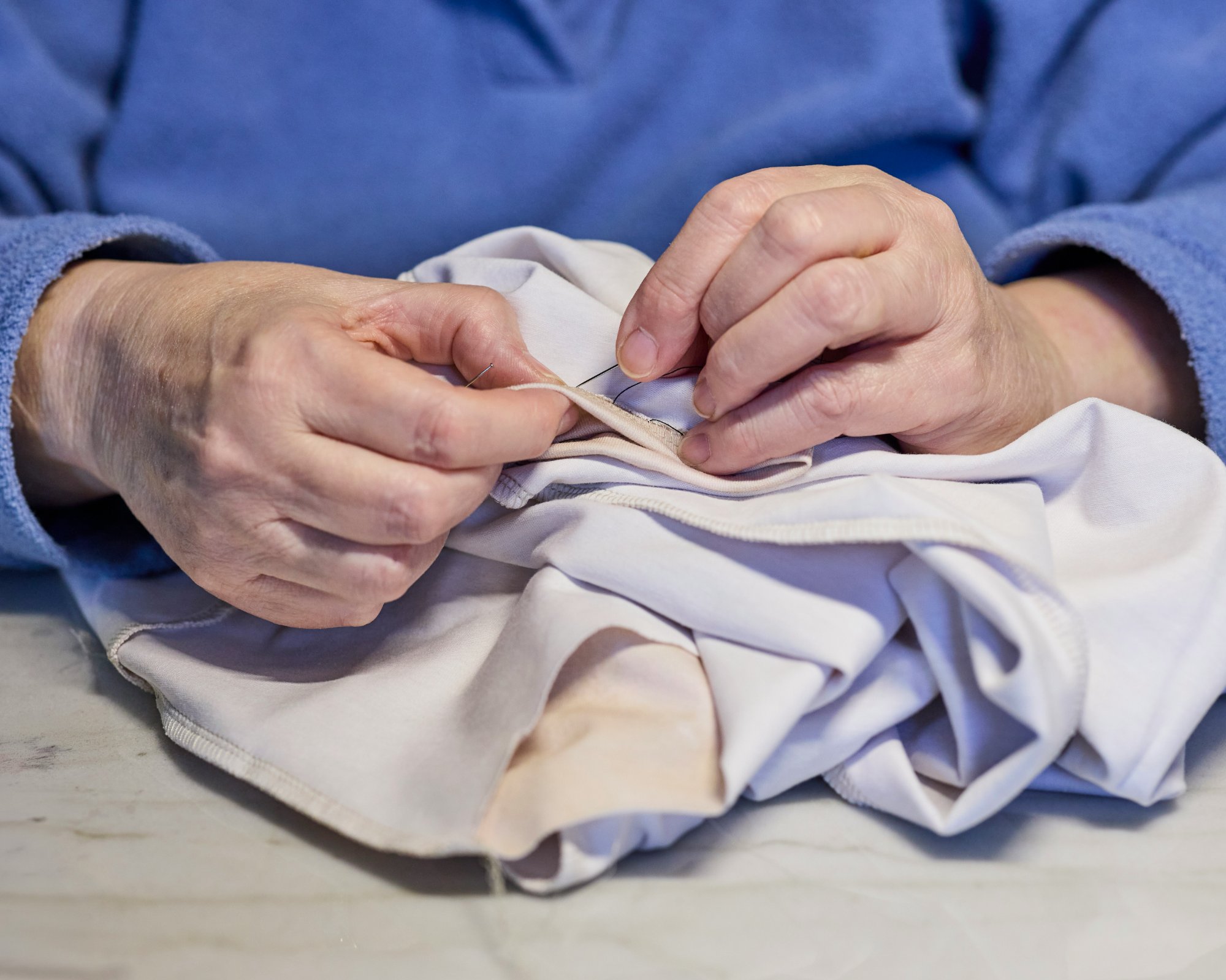 Hands sewing fabric by hand with needle and thread